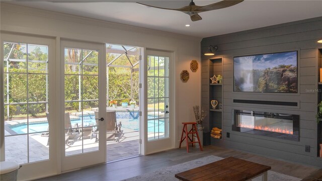 doorway to outside with a glass covered fireplace, ceiling fan, recessed lighting, and wood finished floors