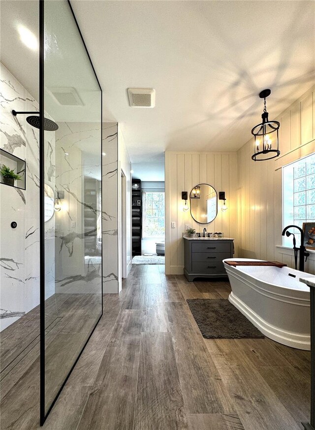 full bath with vanity, a marble finish shower, wood finished floors, and a freestanding tub