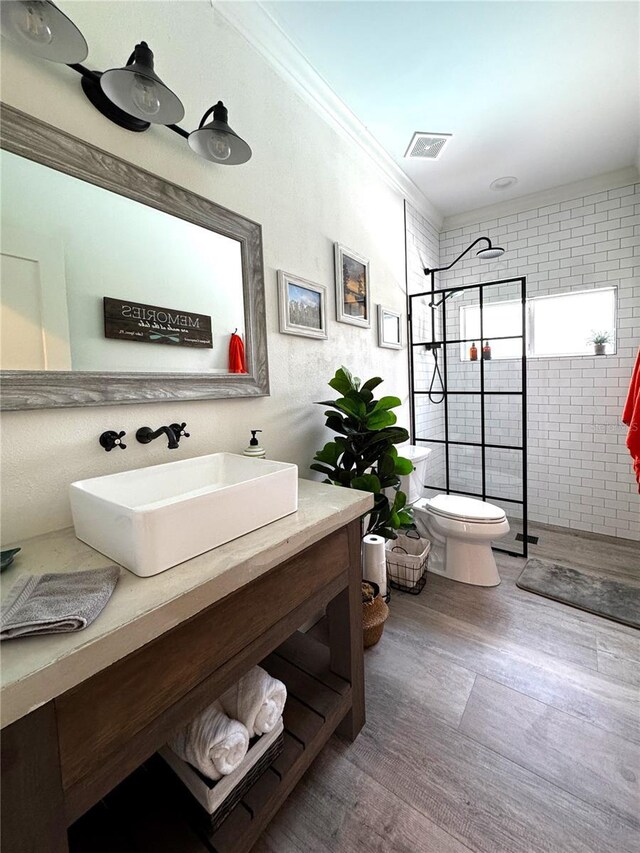 full bath featuring visible vents, ornamental molding, wood finished floors, toilet, and walk in shower