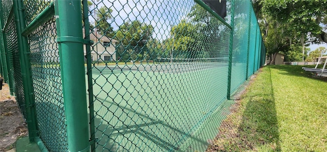 view of tennis court featuring a yard and fence