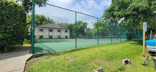view of tennis court featuring fence and a lawn