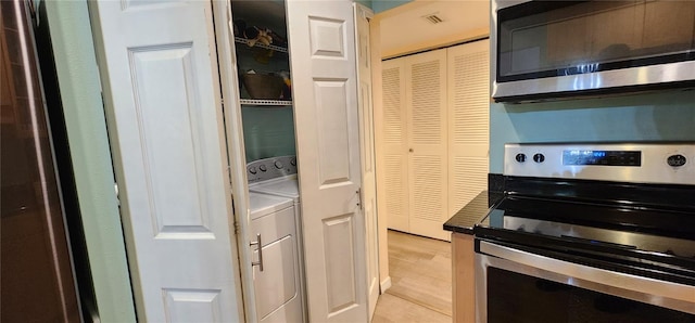 kitchen with stainless steel appliances, washer / dryer, light wood finished floors, and visible vents