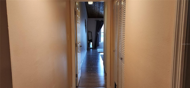 hall featuring a textured wall and dark wood finished floors