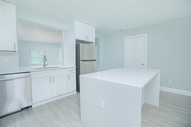 2501 Stratford Dr, Cocoa, FL 32926 - kitchen featuring a sink, appliances with stainless steel finishes, white cabinetry, light countertops, and a center island