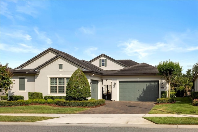 ranch-style home featuring an attached garage, driveway, a front lawn, and stucco siding