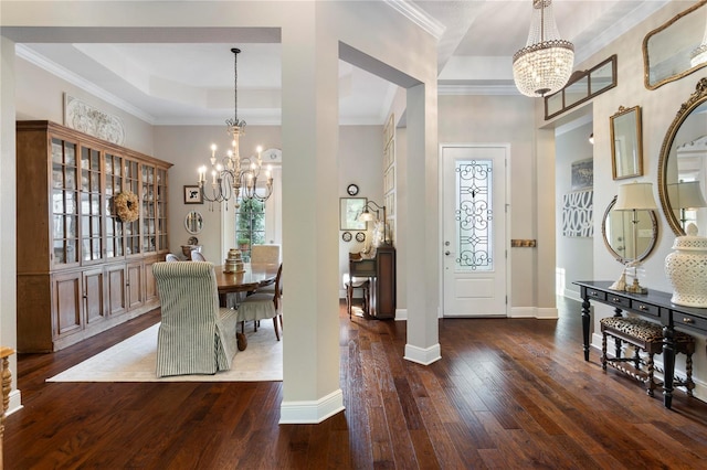 foyer entrance featuring a notable chandelier, ornamental molding, a raised ceiling, and hardwood / wood-style floors