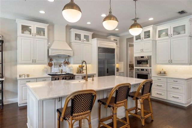 kitchen featuring backsplash, visible vents, premium range hood, white cabinets, and stainless steel appliances