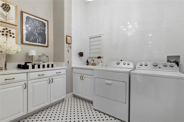 washroom with a sink, cabinet space, and washer and dryer