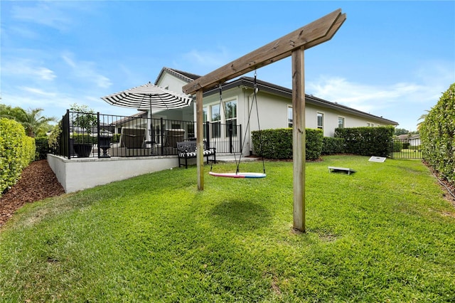 rear view of house with a lawn, fence, and stucco siding