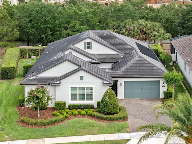 exterior space featuring a garage, a front yard, stucco siding, a tiled roof, and driveway