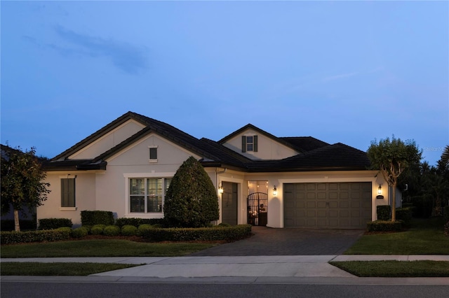 view of front of home featuring an attached garage, stucco siding, driveway, and a front yard