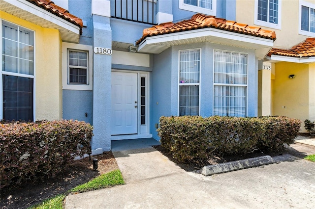 1180 S Beach Cir, Kissimmee, FL 34746 - view of exterior entry featuring a tiled roof and stucco siding