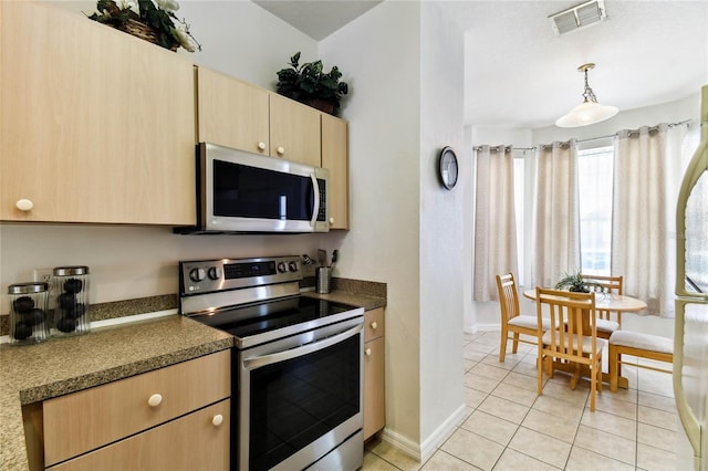 1180 S Beach Cir, Kissimmee, FL 34746 - kitchen featuring appliances with stainless steel finishes, light brown cabinetry, light tile patterned flooring, decorative light fixtures, and baseboards