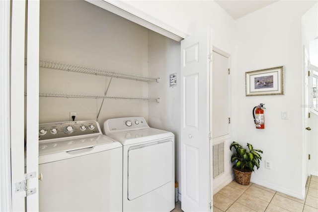 1180 S Beach Cir, Kissimmee, FL 34746 - laundry area with washing machine and dryer, light tile patterned floors, and baseboards