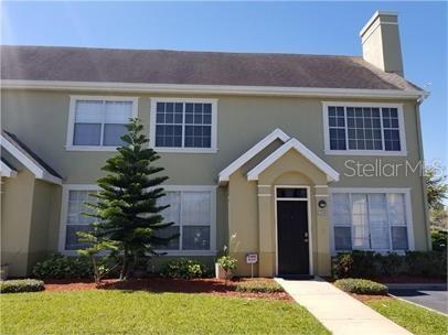 8973 Lee Vista Blvd Unit 2308, Orlando, FL 32829 - view of front of house featuring stucco siding, a chimney, and a front yard