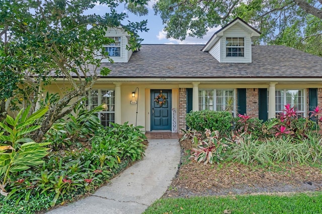 new england style home with a shingled roof and covered porch