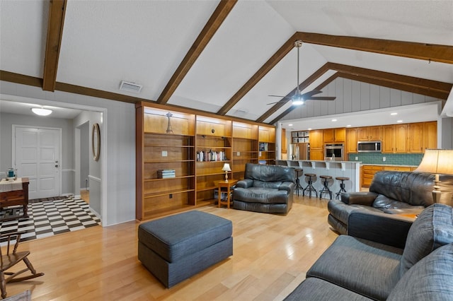 living room with visible vents, lofted ceiling with beams, light wood-style flooring, and a ceiling fan