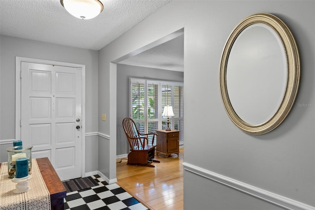 foyer entrance featuring tile patterned floors, baseboards, and a textured ceiling