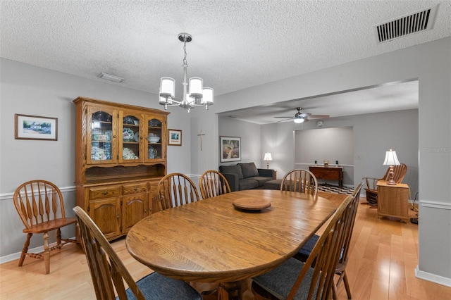 dining space with light wood finished floors, a textured ceiling, and visible vents