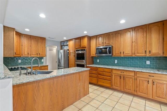 kitchen featuring a sink, appliances with stainless steel finishes, tasteful backsplash, and brown cabinets