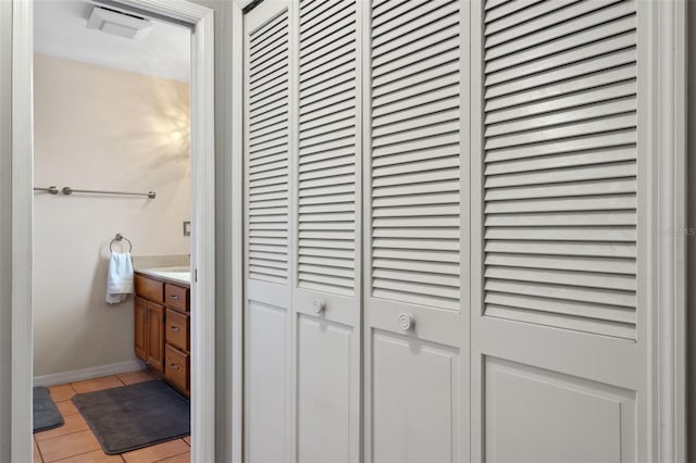 interior space with vanity, tile patterned floors, baseboards, and a closet