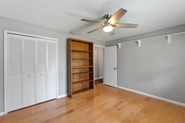unfurnished bedroom with light wood-type flooring, a ceiling fan, a textured ceiling, and a closet