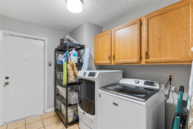 laundry room with a textured ceiling, washing machine and dryer, cabinet space, and light tile patterned flooring