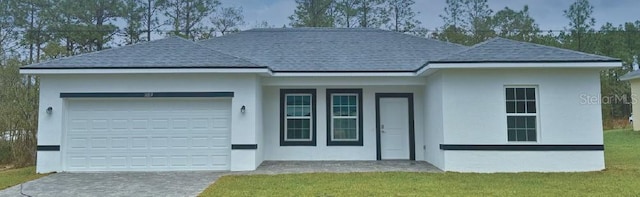 ranch-style house featuring a shingled roof, a garage, stucco siding, a front yard, and driveway