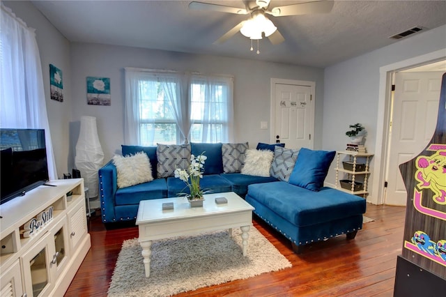 living room with visible vents, dark wood-style flooring, and ceiling fan
