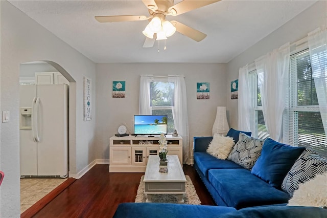 living area with arched walkways, baseboards, a ceiling fan, and wood finished floors