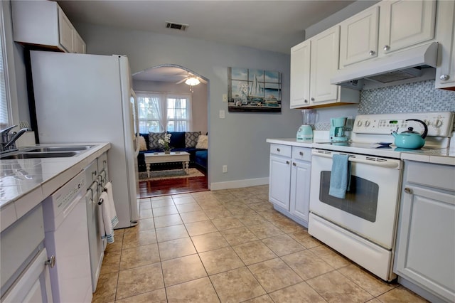 kitchen with visible vents, arched walkways, a sink, under cabinet range hood, and white appliances