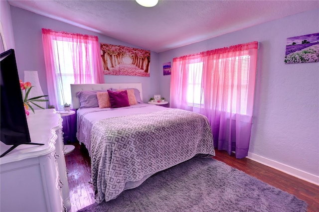 bedroom with baseboards, vaulted ceiling, and wood finished floors