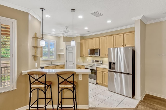 kitchen featuring a peninsula, light brown cabinets, ceiling fan, a sink, and stainless steel appliances