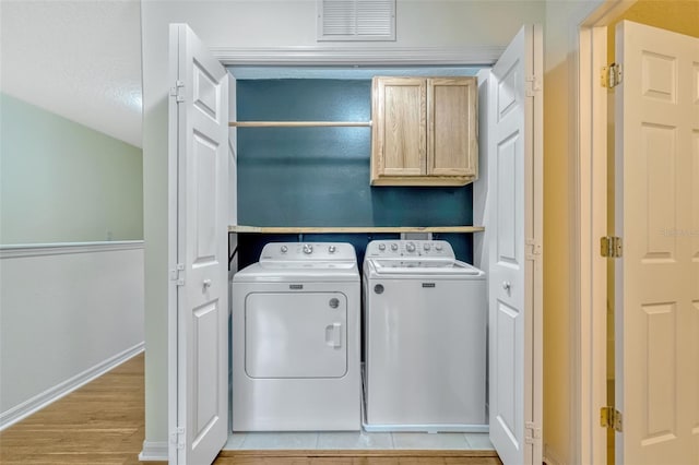 laundry area with visible vents, cabinet space, baseboards, light wood finished floors, and separate washer and dryer
