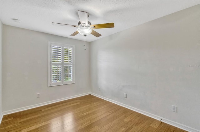spare room featuring a ceiling fan, baseboards, wood finished floors, and a textured ceiling