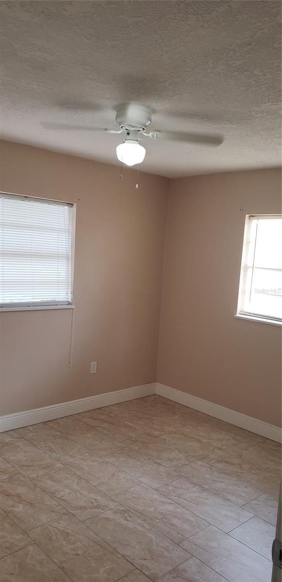 unfurnished room featuring baseboards, ceiling fan, and a textured ceiling