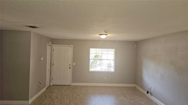 unfurnished room featuring baseboards, a textured ceiling, and visible vents