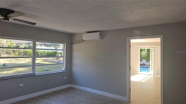 spare room featuring an AC wall unit, ceiling fan, baseboards, and a textured ceiling