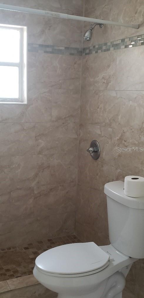 full bath featuring toilet and a tile shower