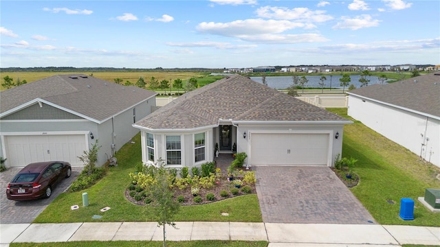 single story home featuring driveway, roof with shingles, a garage, a front lawn, and stucco siding