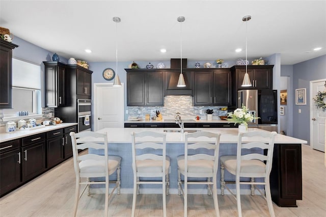 kitchen with backsplash, light countertops, appliances with stainless steel finishes, and a kitchen bar