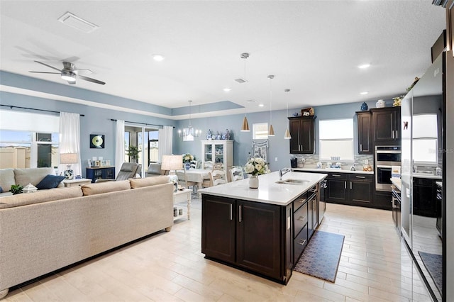 kitchen with visible vents, light countertops, a sink, light wood finished floors, and open floor plan