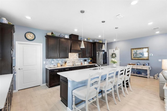 kitchen featuring a breakfast bar area, visible vents, dark brown cabinets, light countertops, and light wood-style floors