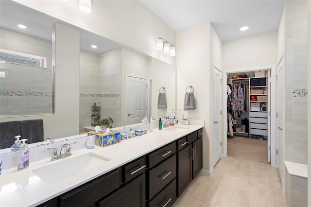 full bathroom featuring a sink, a walk in closet, walk in shower, and double vanity