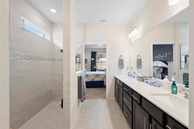 ensuite bathroom with a sink, ensuite bath, and a healthy amount of sunlight