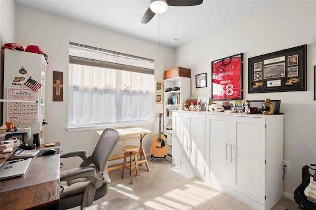 office space featuring baseboards, a ceiling fan, and light carpet
