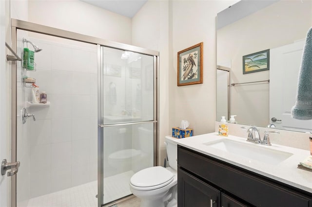 bathroom featuring vanity, a shower stall, and toilet