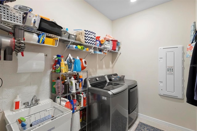 laundry area with laundry area, washing machine and dryer, light tile patterned flooring, baseboards, and a sink