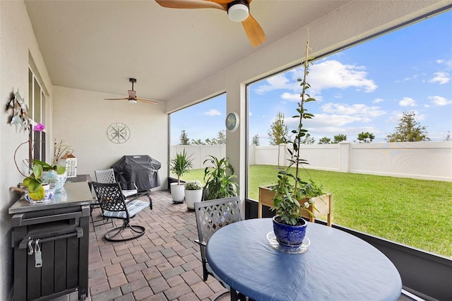 sunroom / solarium featuring outdoor dining area and a ceiling fan