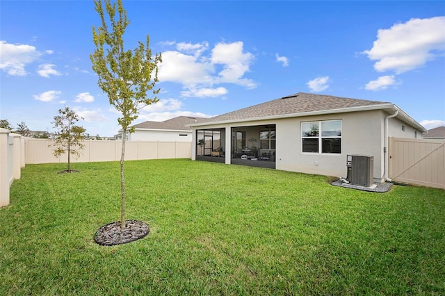 rear view of house featuring a sunroom, a fenced backyard, central AC, and a yard